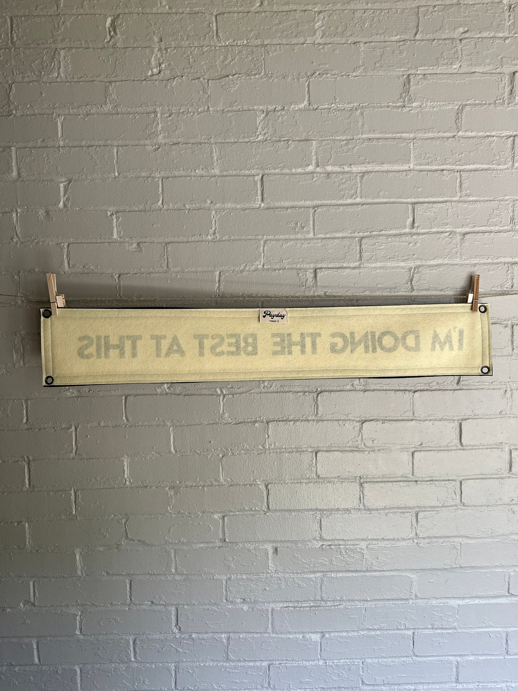 Back of a cream banner with black trim and lettering that reads "I'm doing the best at this"