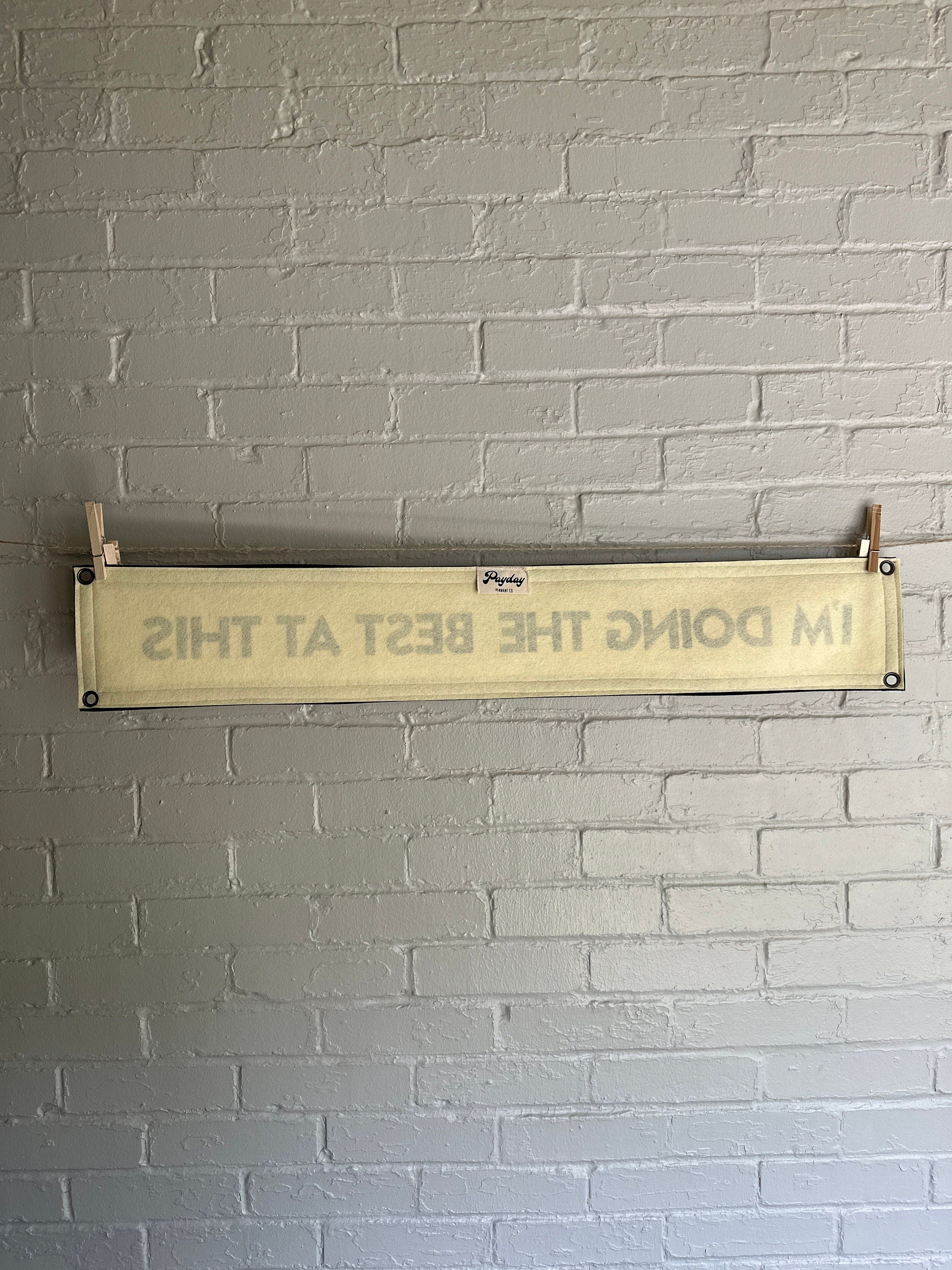 Back of a cream banner with black trim and lettering that reads "I'm doing the best at this"