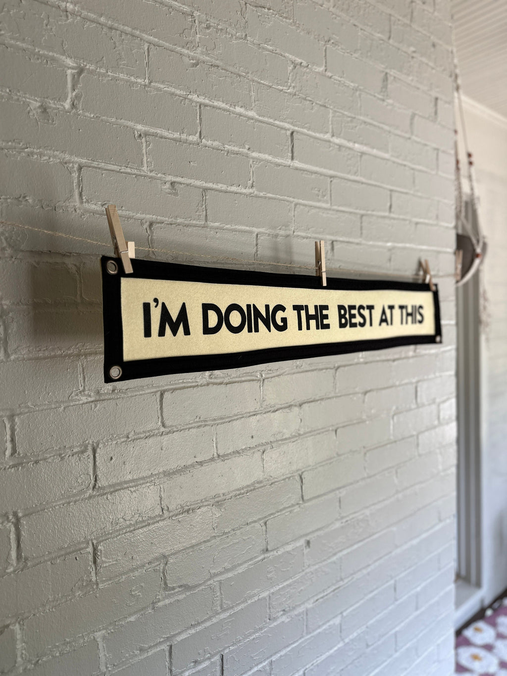 Side view of a cream banner with black trim and lettering that reads "I'm doing the best at this"