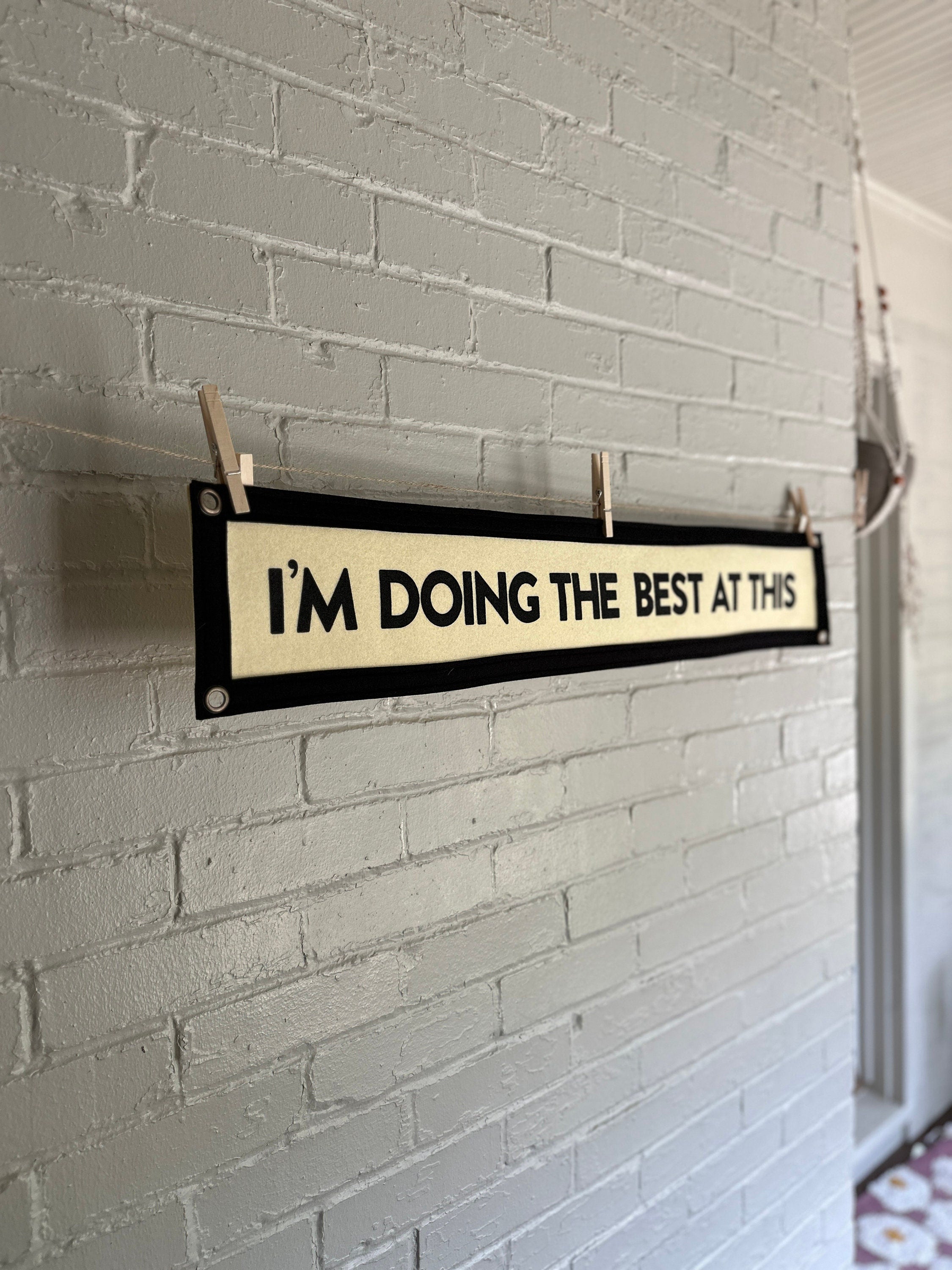 Side view of a cream banner with black trim and lettering that reads "I'm doing the best at this"