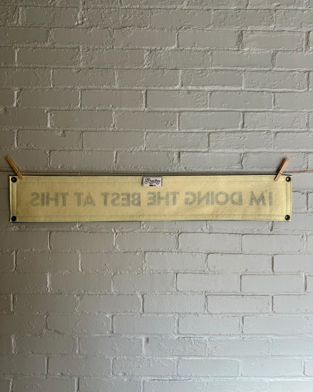 Back of a cream banner with green trim and lettering that reads "I'm doing the best at this"