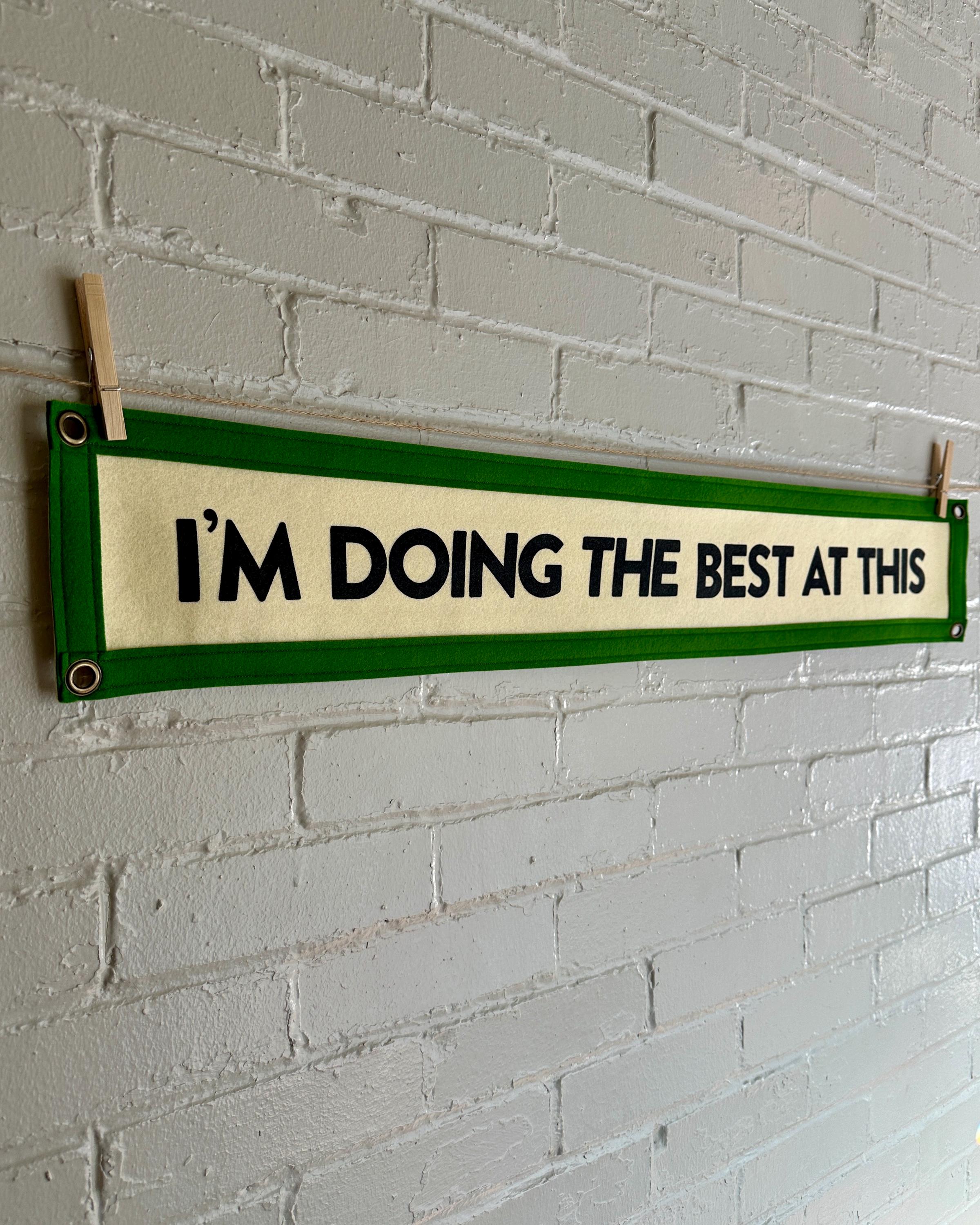 Side of a cream banner with green trim and black lettering that reads "I'm doing the best at this"