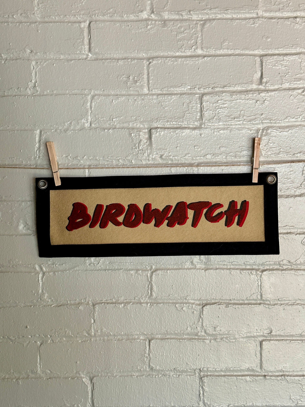 Light brown banner with black trim and double printed red and black lettering reading "BIRDWATCH"