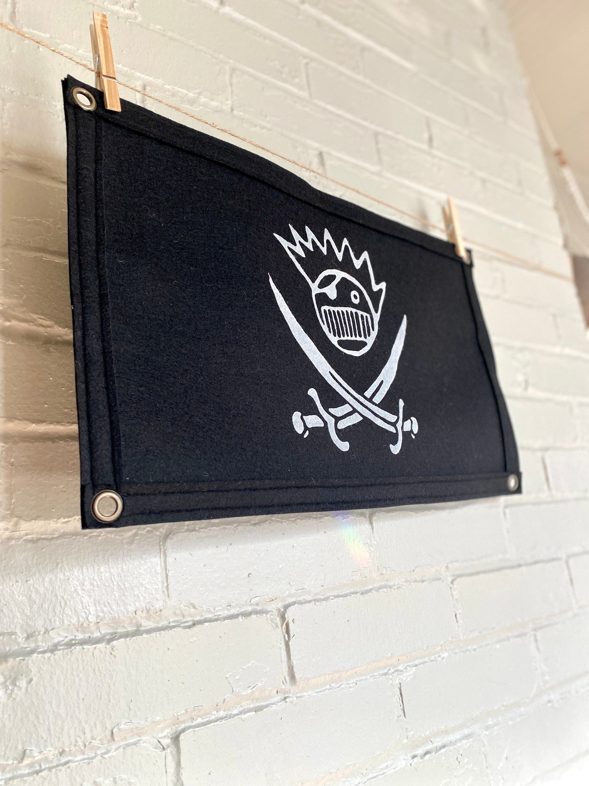 Side view of a large black felt banner with a jolly roger boognish design printed in white ink
