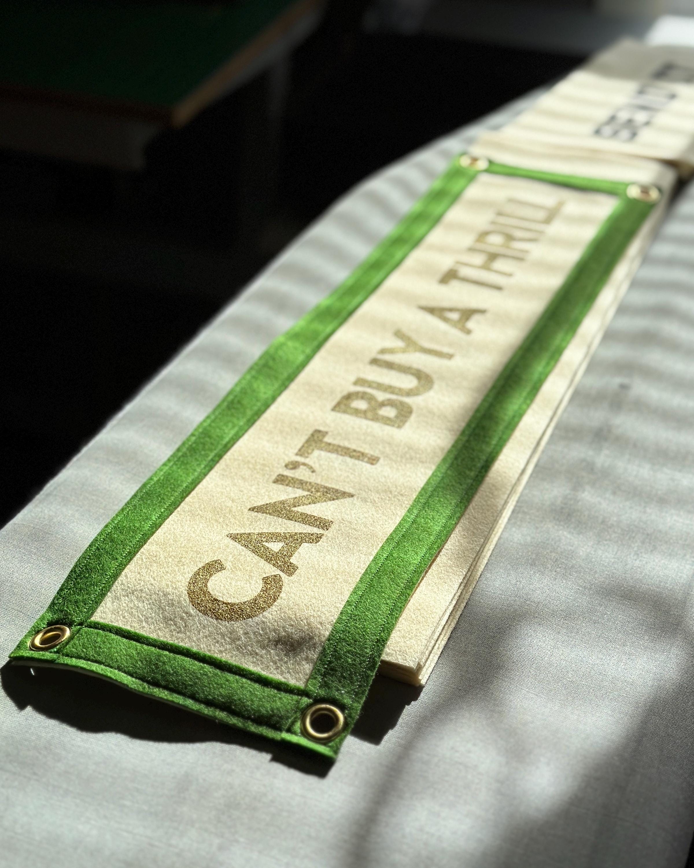 Several "Can't Buy a Thrill" banners in progress captured in moody sunlight on an ironing board