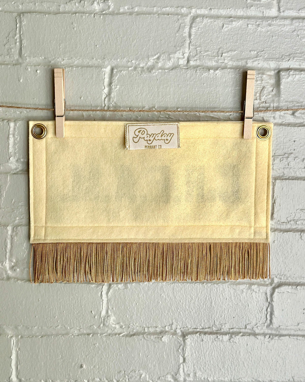 Back of a cream felt banner with cream trim and gold fringe, and gold lettering that reads 'C.R.E.A.M.'