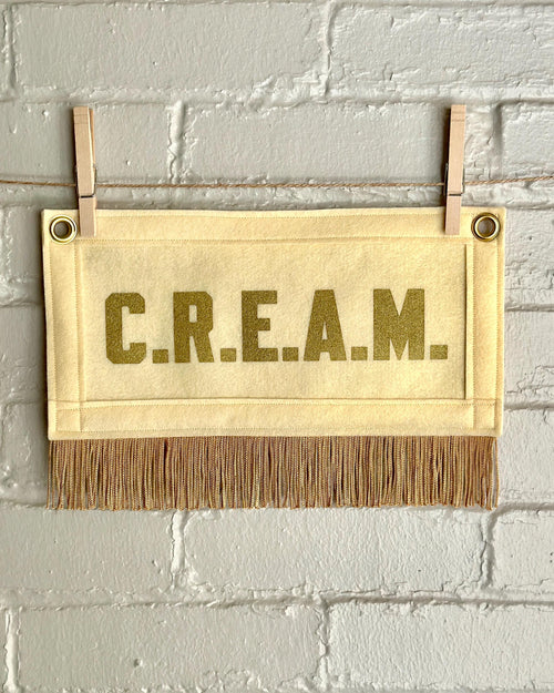 Cream felt banner with cream trim and gold fringe, and gold lettering that reads 'C.R.E.A.M.'