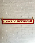 A cream felt banner with red trim and lettering that reads "I didn't do fucking shit"