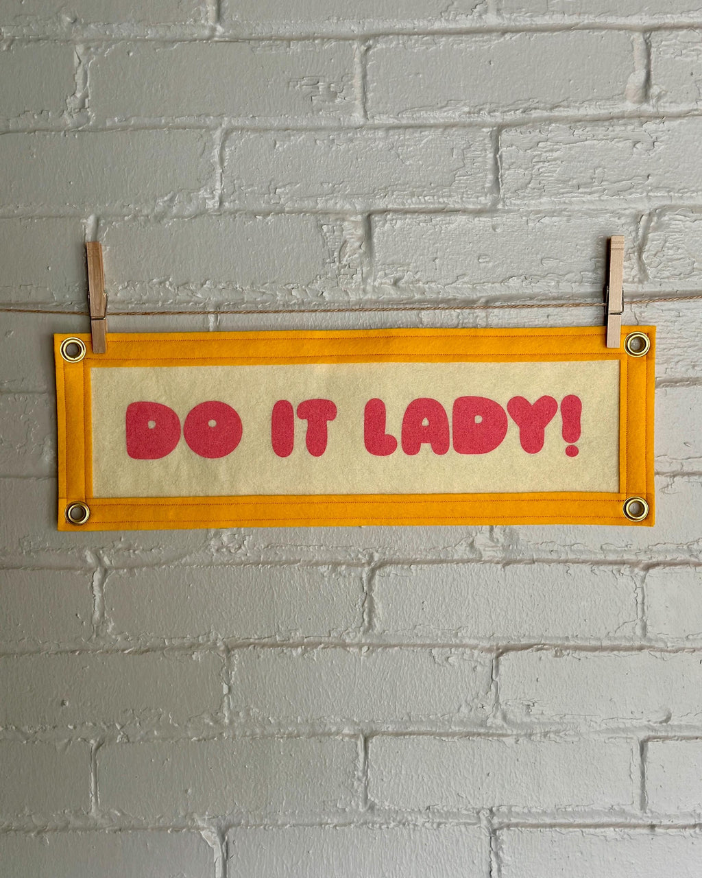 A cream felt banner with yellow trim and pink lettering that reads "Do it lady!"