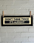 A cream banner with black trim and lettering that reads "Don't Think Twice It's Alright"