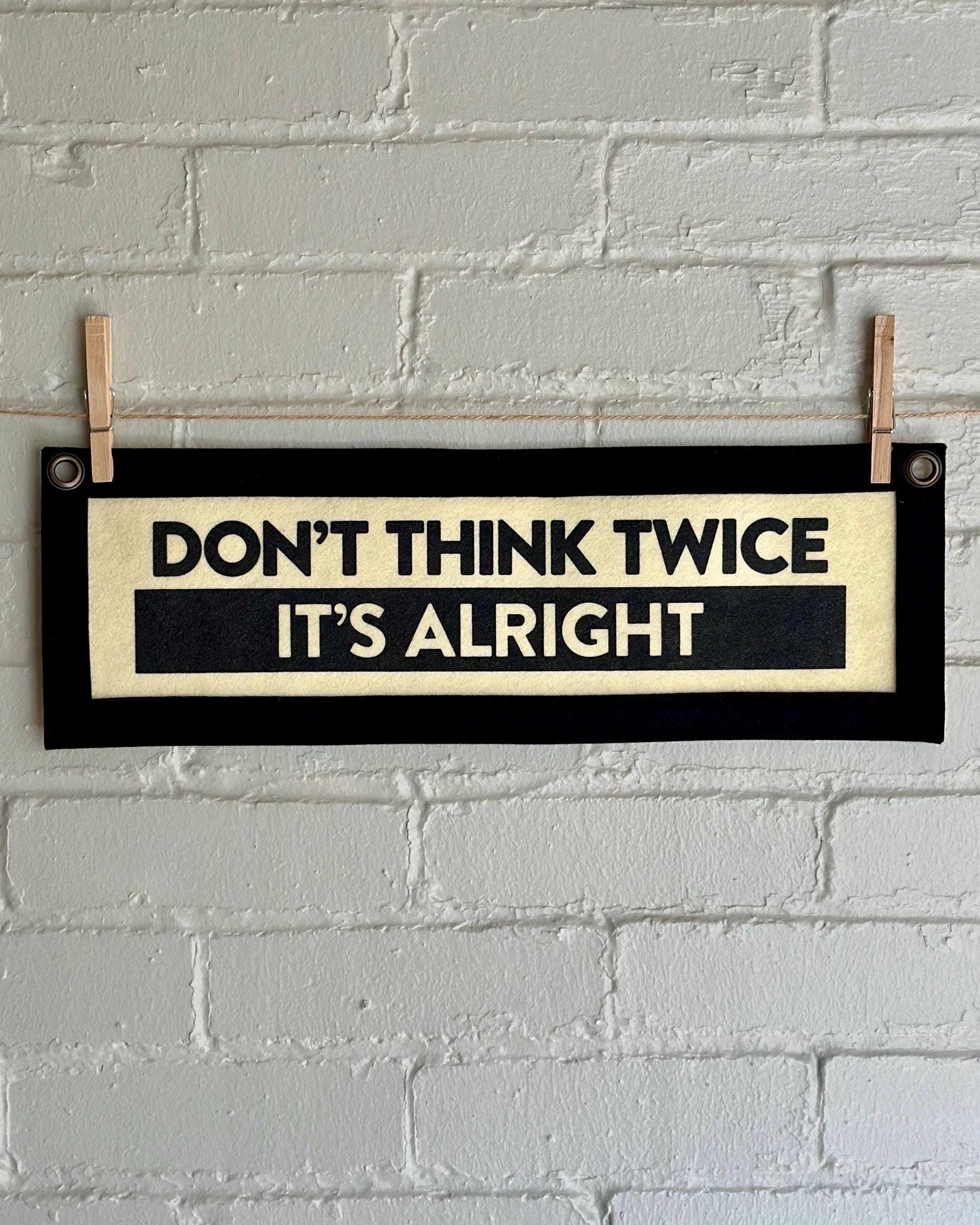 A cream banner with black trim and lettering that reads "Don't Think Twice It's Alright"