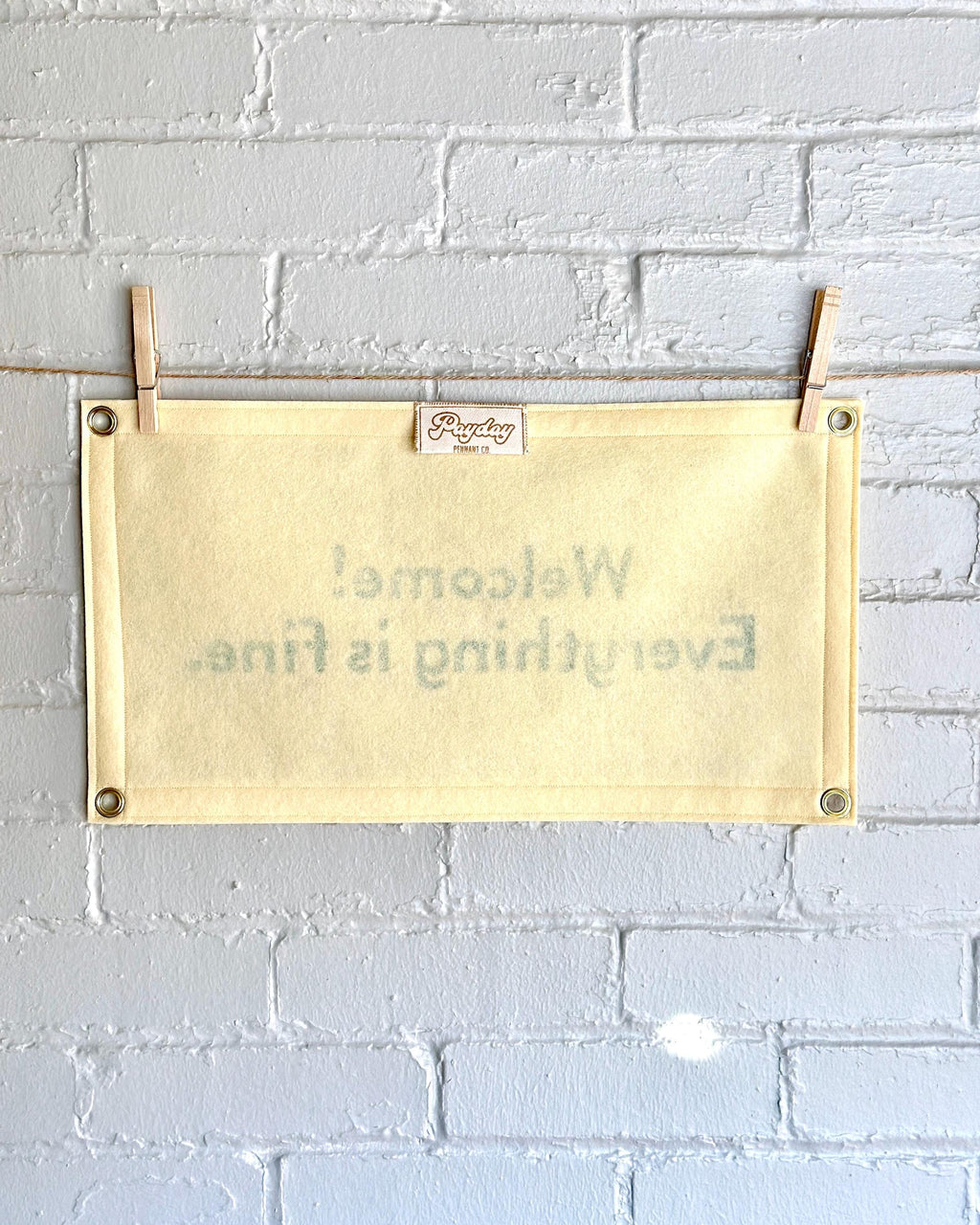 Back of a cream felt banner with green lettering referencing The Good Place reading "Welcome! Everything is fine."