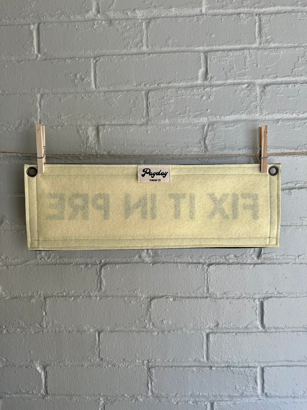 The back of a cream banner with black trim and lettering that reads "Fix it in Pre"