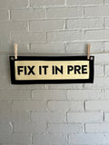 A cream banner with black trim and lettering that reads "Fix it in Pre"
