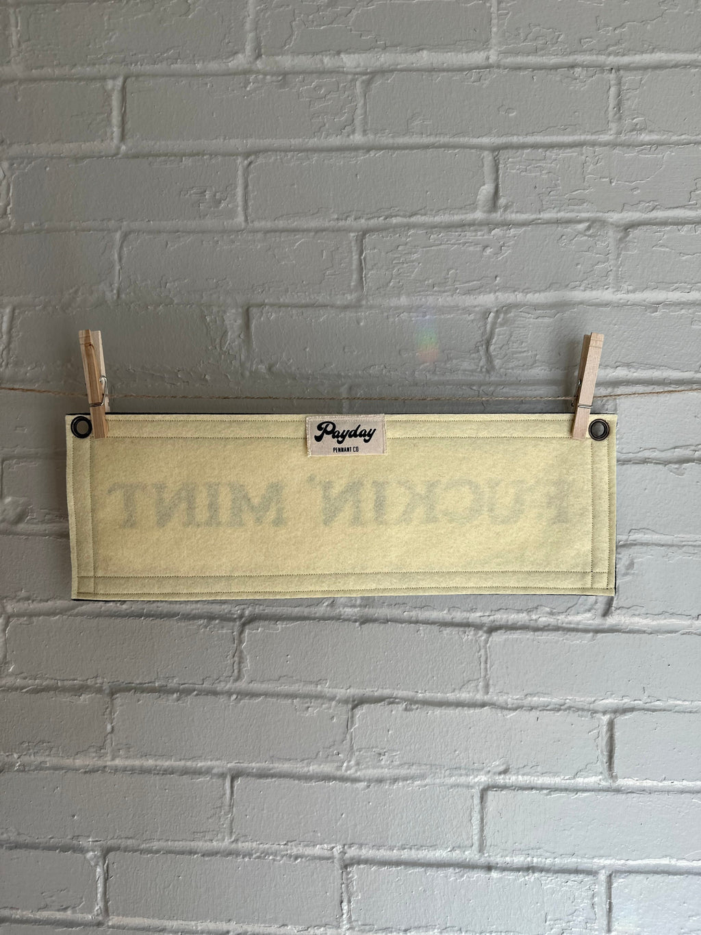 Back of a cream felt banner with black trim and lettering that reads "fuckin' mint"