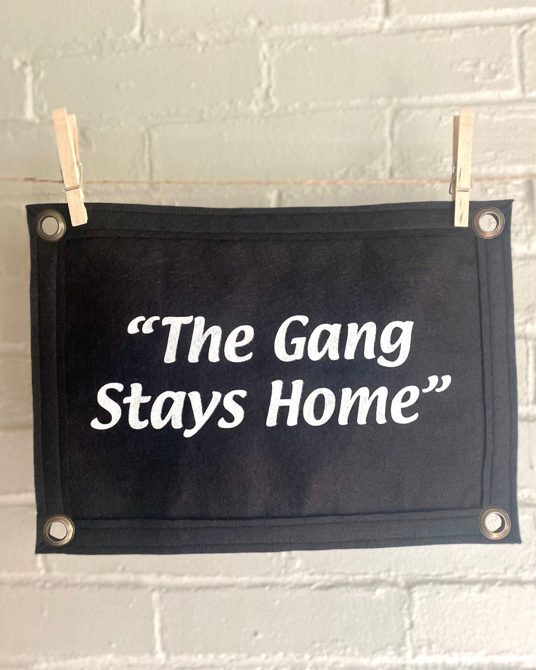 A black banner with black felt trim and white lettering that reads "the gang stays home"