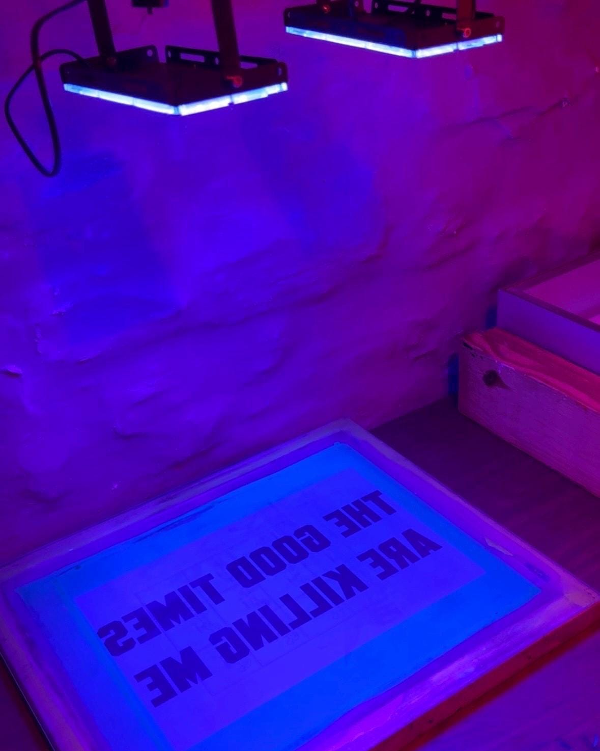 UV lights shining on a silkscreen with The Good Times Killing me design on top