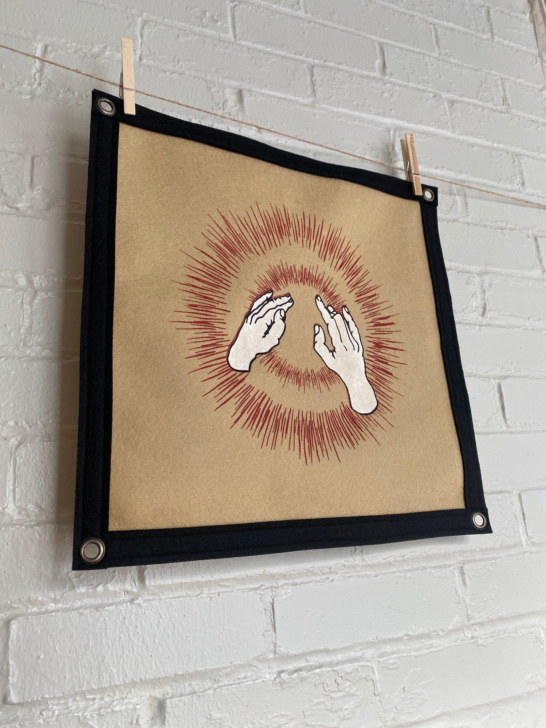 Side view of a light brown felt banner with black trim, and album art from band Godspeed You! Black Emperor