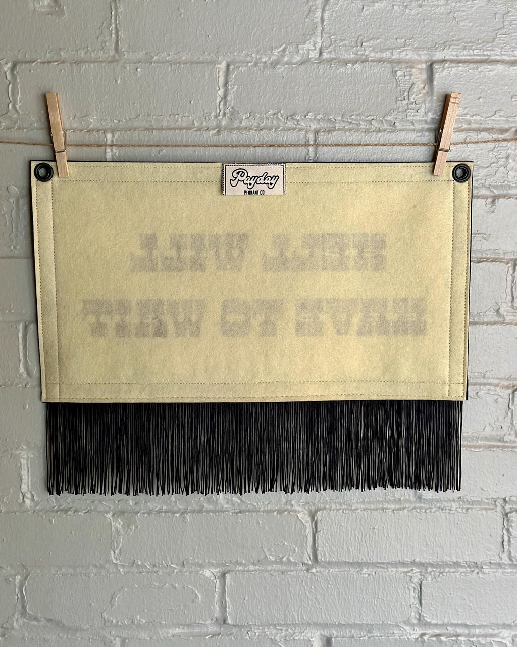 Back of a cream felt banner with black trim, long black fringe, and blood red lettering reading "Hell will have to wait"