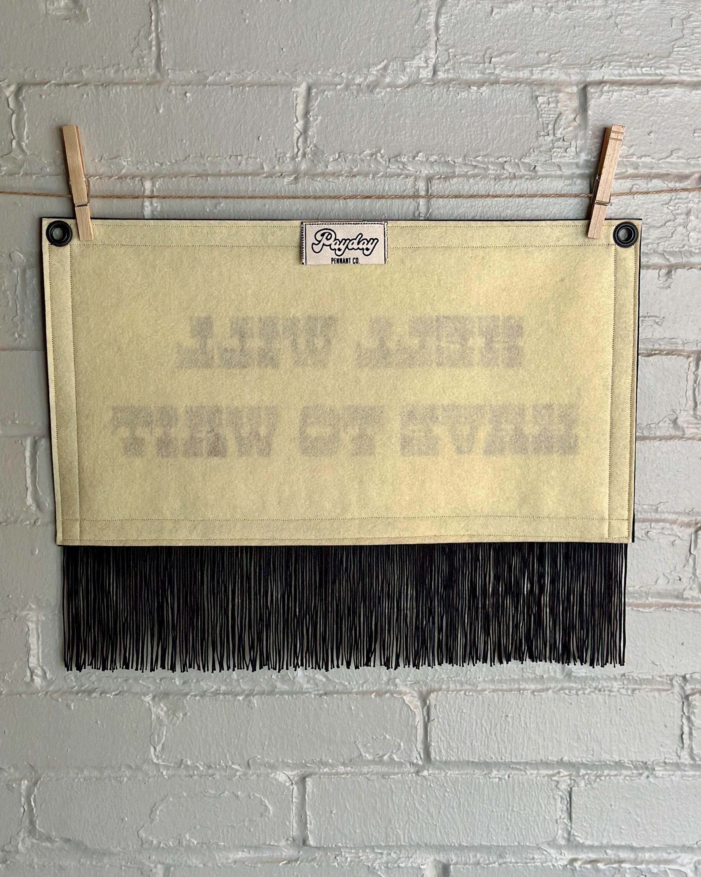 Back of a cream felt banner with black trim, long black fringe, and blood red lettering reading "Hell will have to wait"