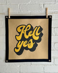 A light brown banner with black trim and a large stylized vintage lettering in black and yellow ink that reads "Hell yes"