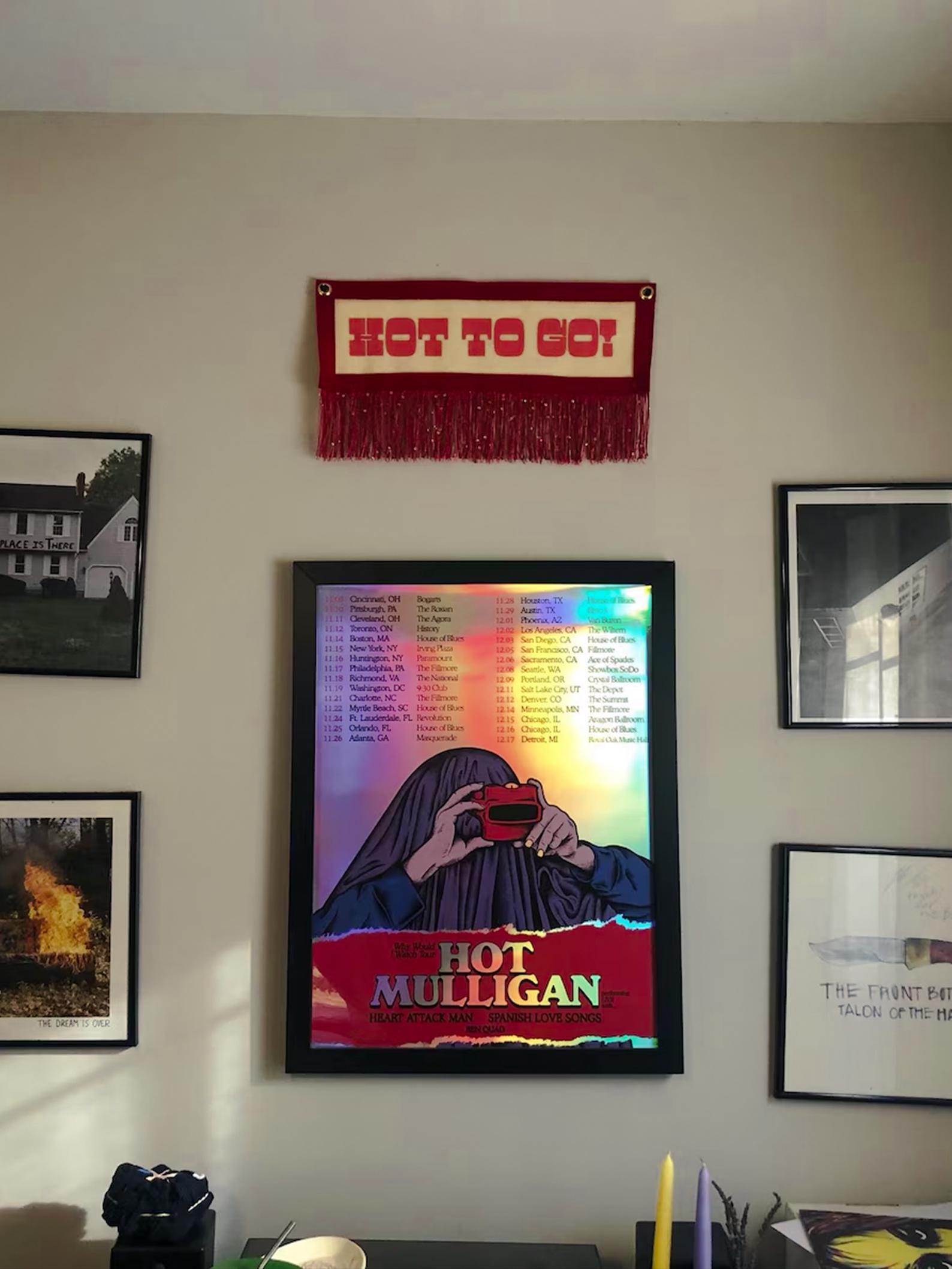 A red HOT GO GO! banner hung on a beige wall alongside other framed artwork and band posters