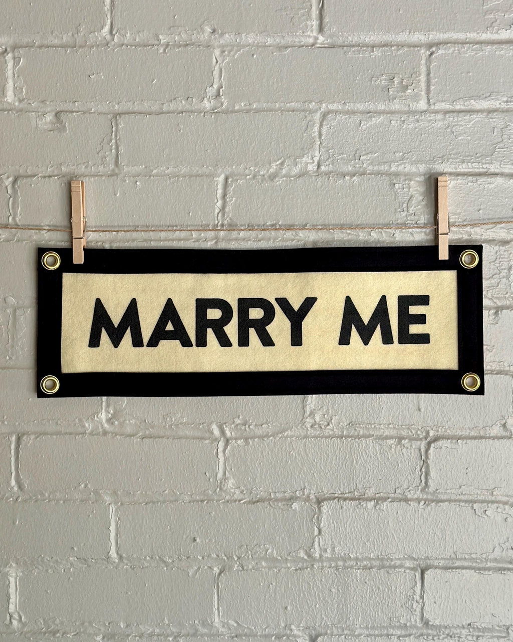 Cream felt banner with black trim and lettering reading 'MARRY ME'