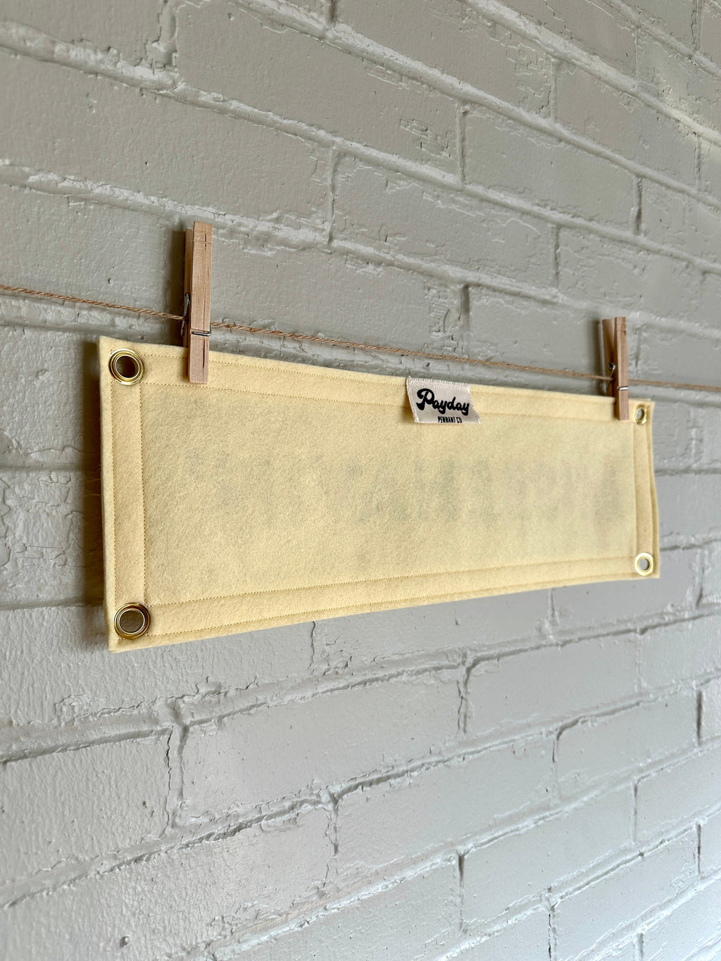 Back of a cream felt banner with cream trim and gold ink lettering that reads "MISBEHAVIN'"