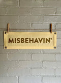 Cream felt banner with cream trim and gold ink lettering that reads "MISBEHAVIN'"