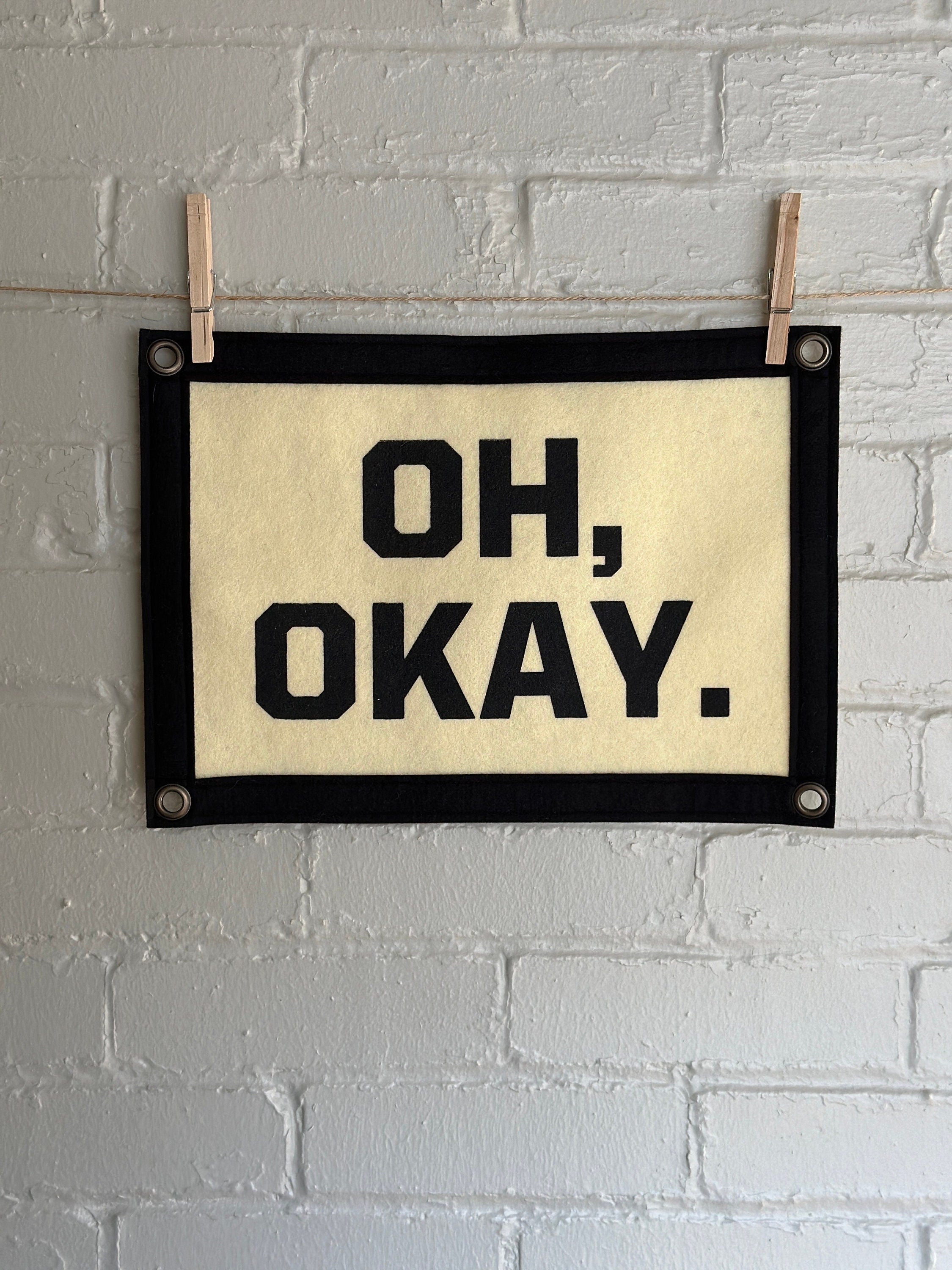Cream banner with black felt trim and lettering that reads "Oh, Okay."