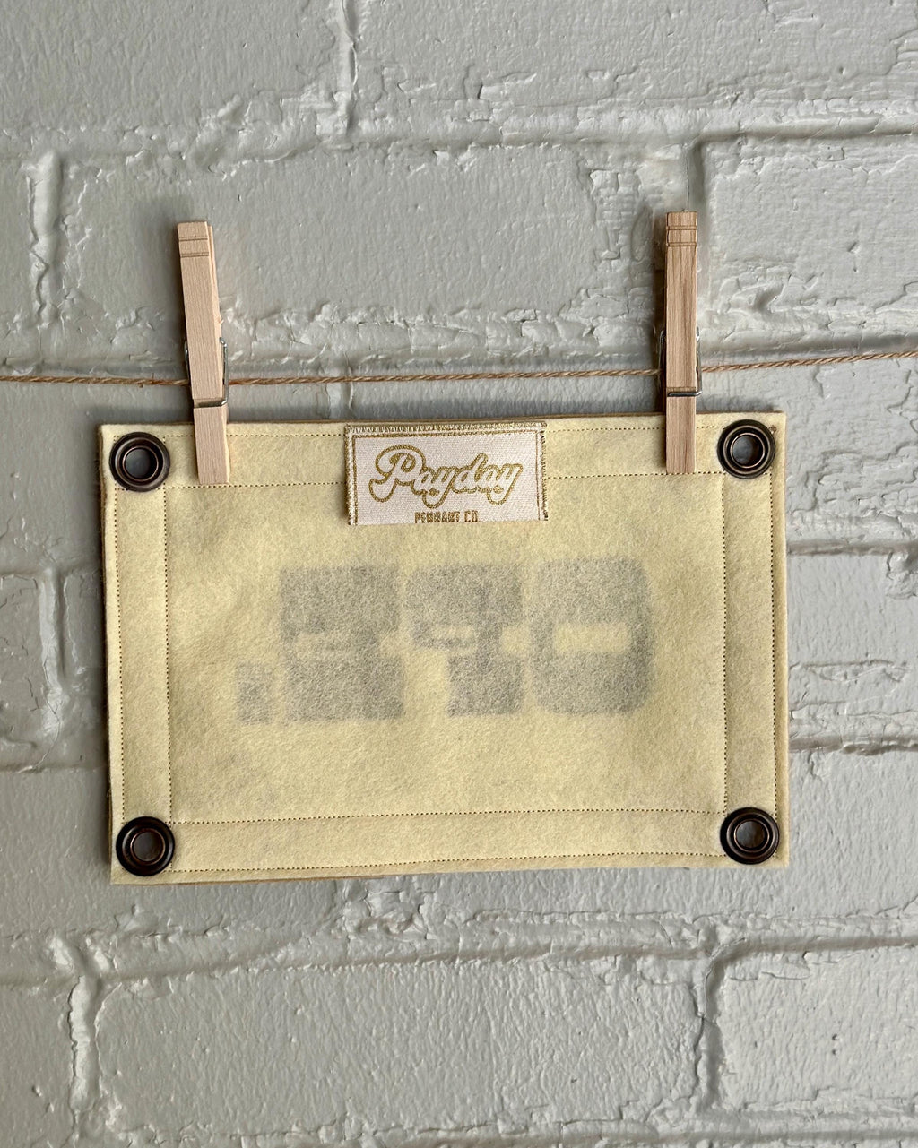 Back of a cream felt banner with light brown trim and brown ink reading "OPE."