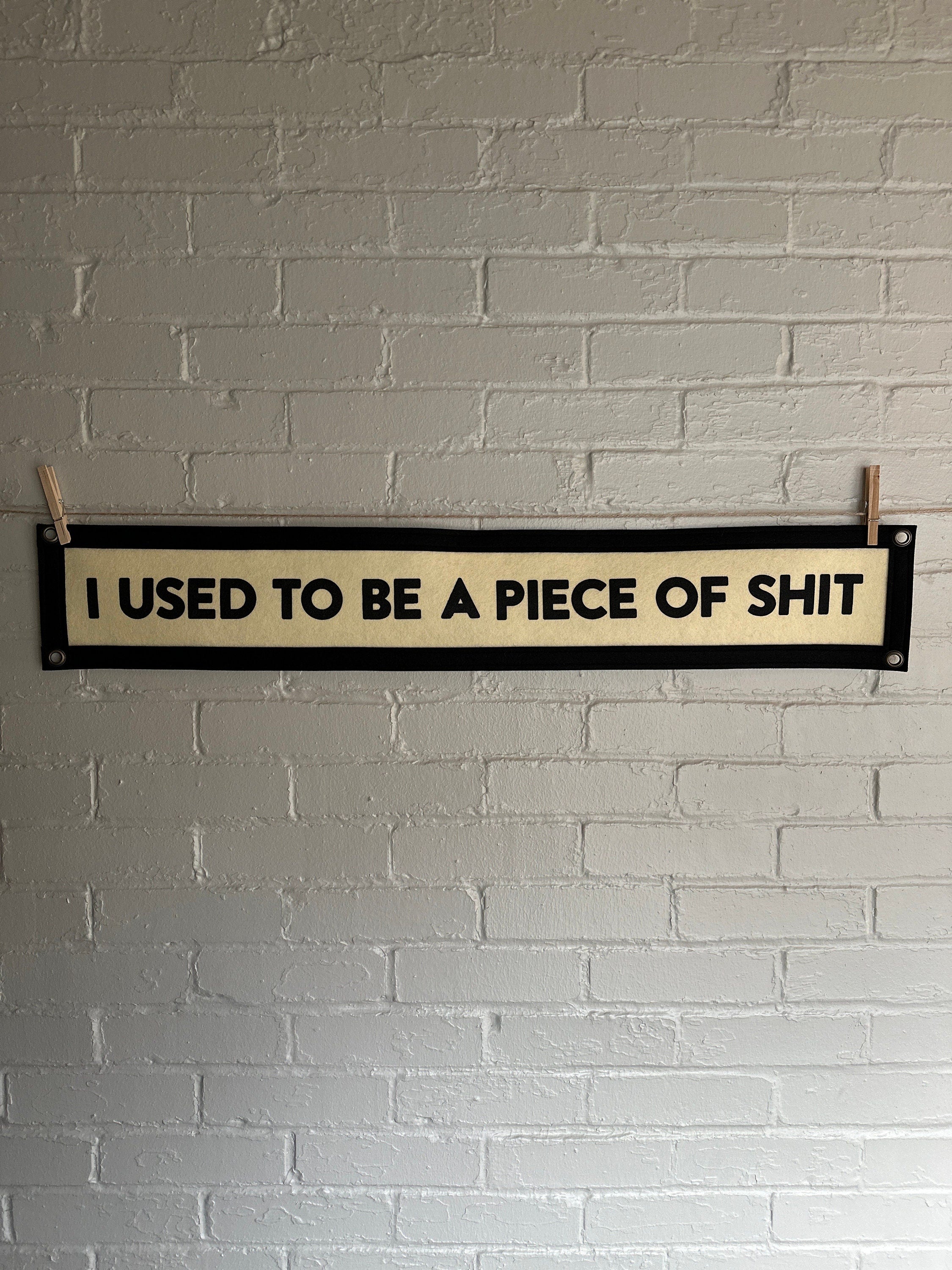 A cream banner with black trim and lettering that reads "I used to be a piece of shit"