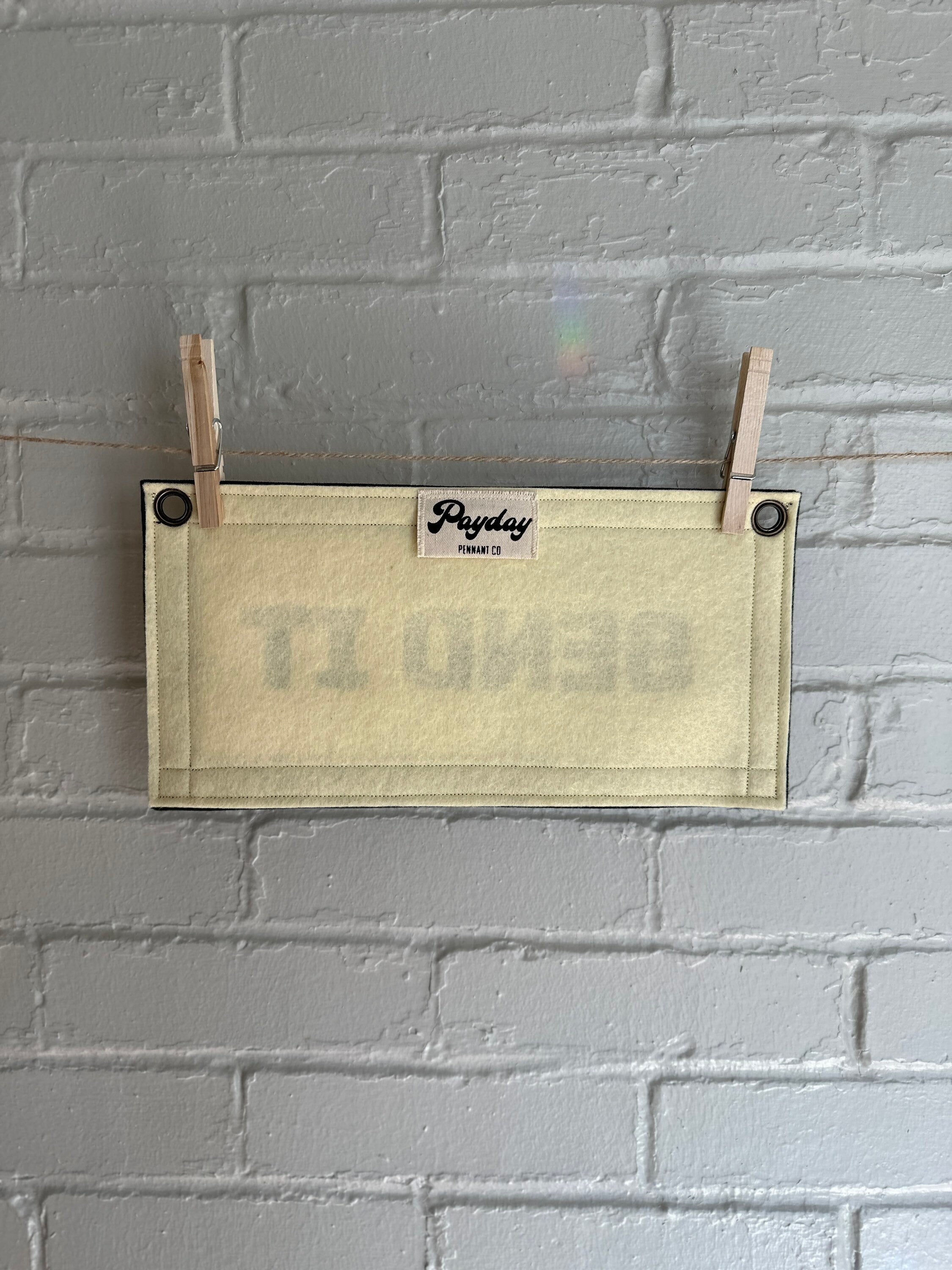 Back of a cream felt banner with black trim and lettering that reads "SEND IT"