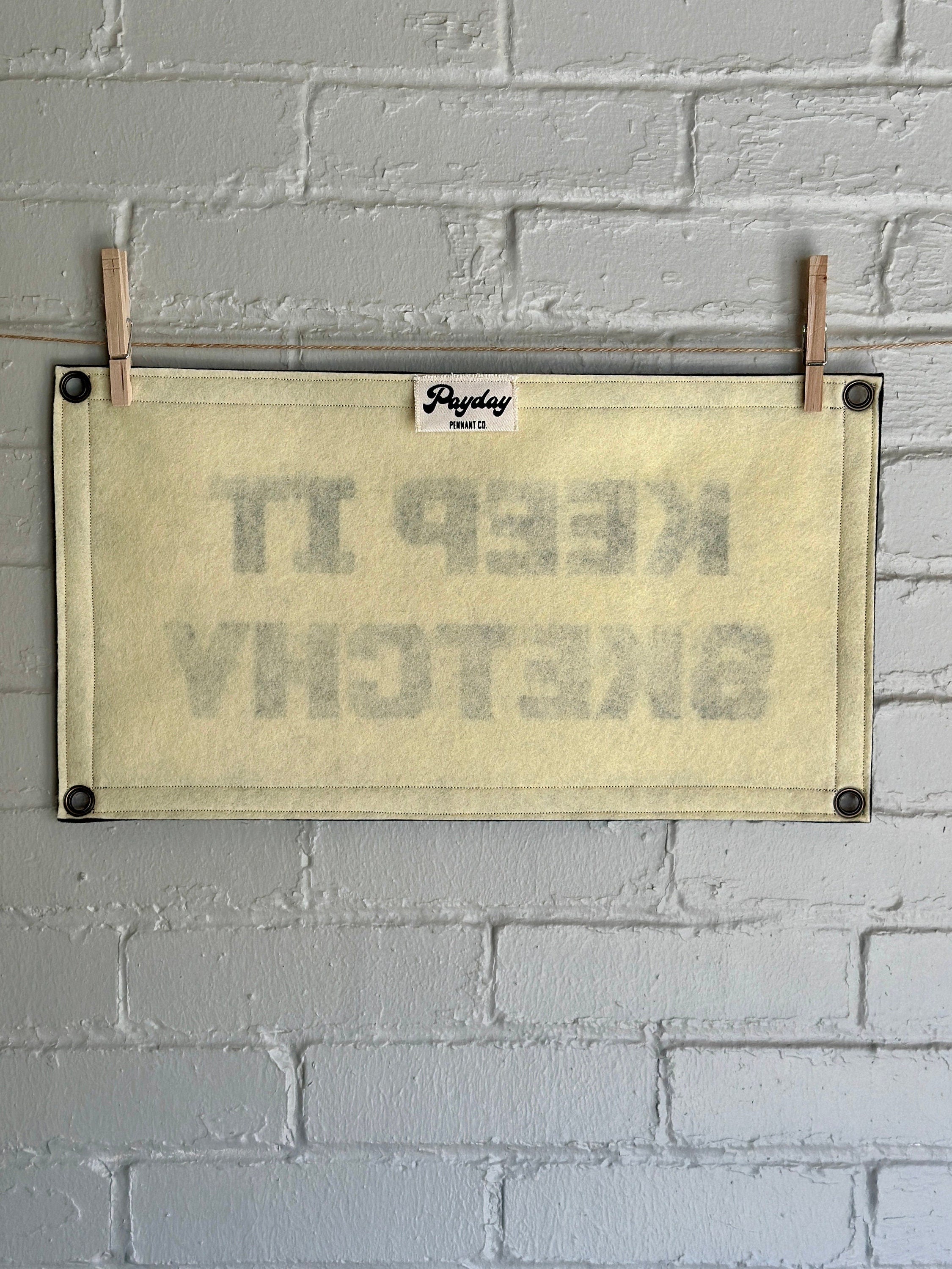 The back of a cream banner with black trim and lettering that reads "Keep it Sketchy"