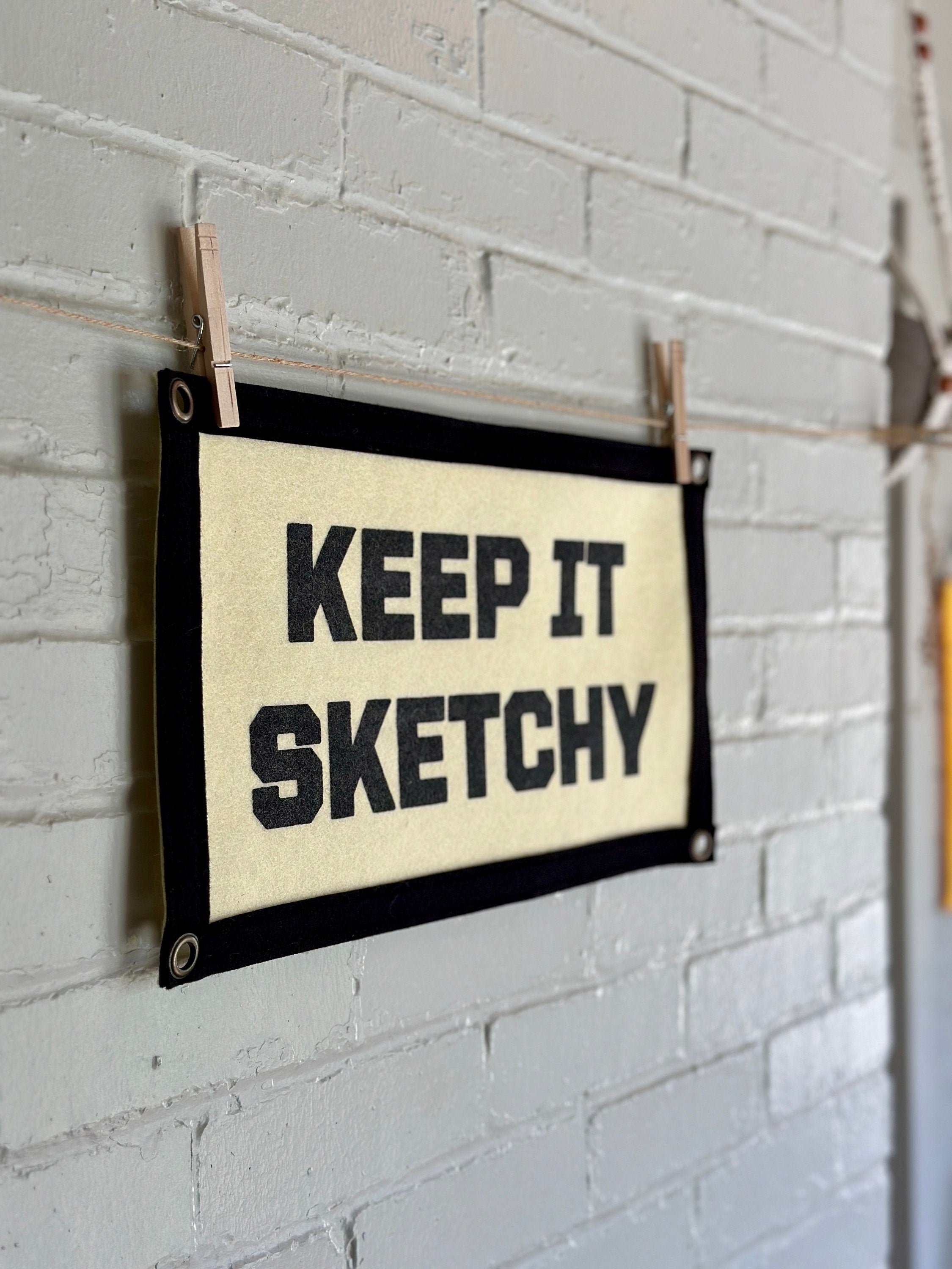 The side of a cream banner with black trim and lettering that reads "Keep it Sketchy"