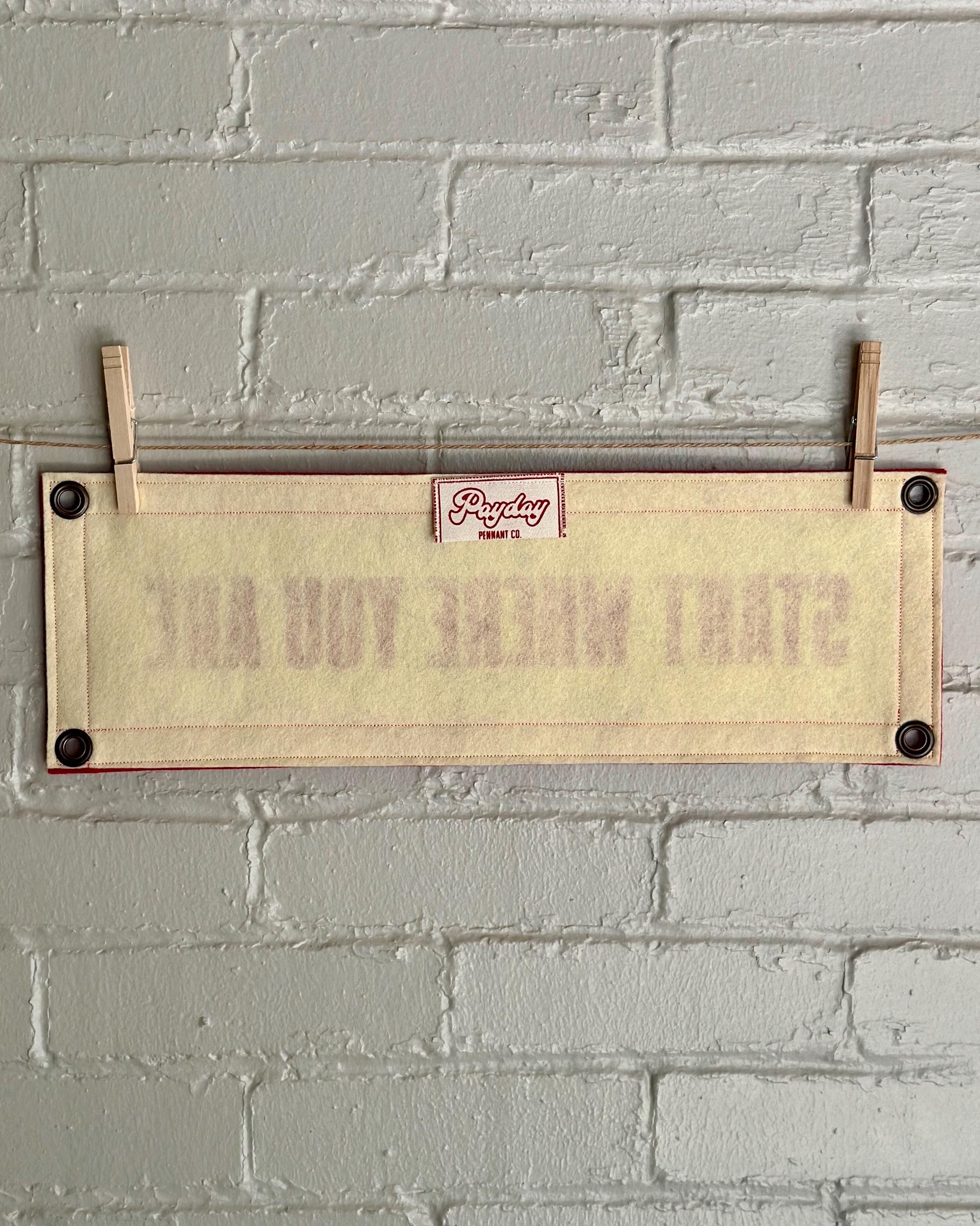 Back of a cream felt banner with red trim and lettering that reads "Start where you are"