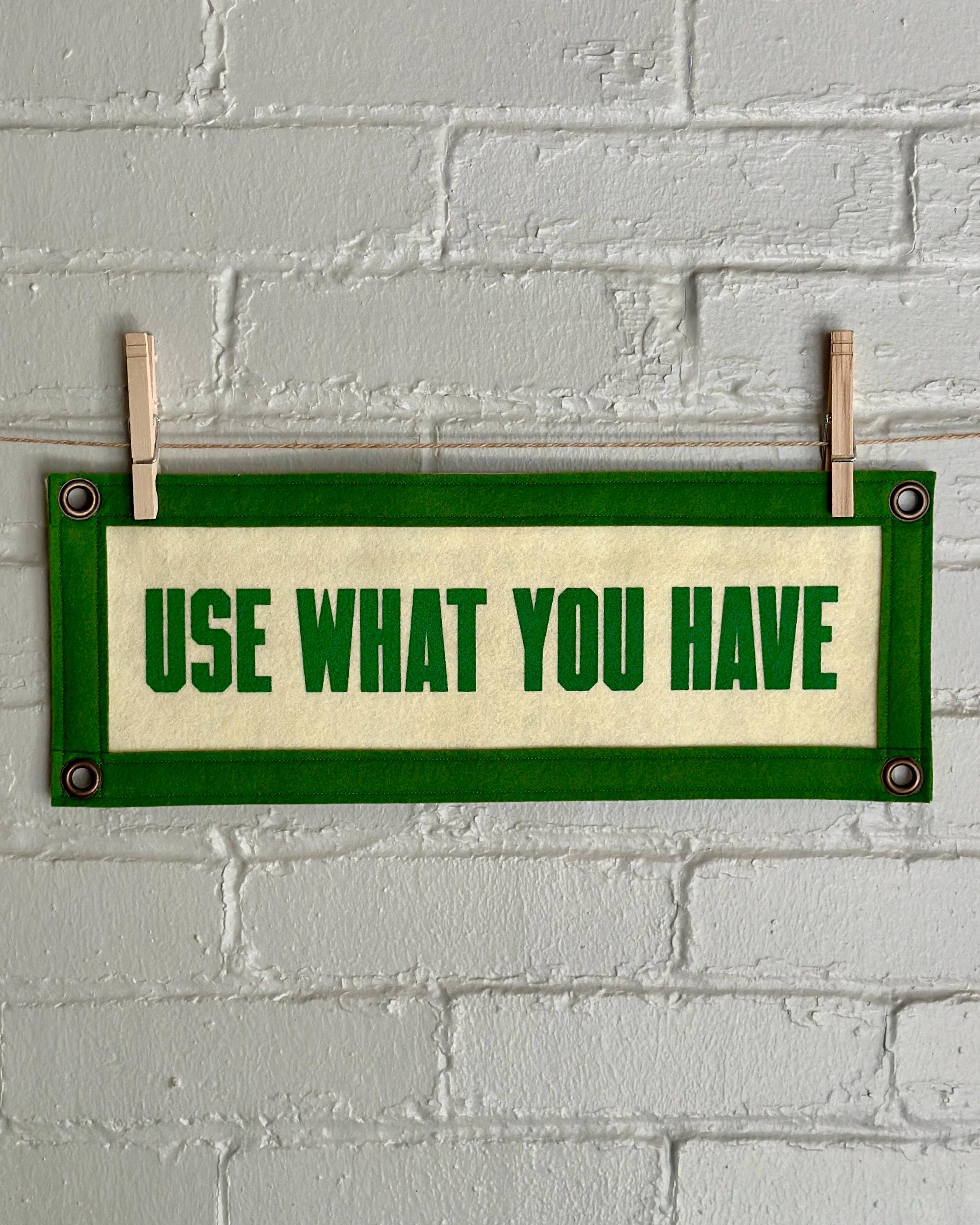 A cream felt banner with green trim and lettering that reads "Use what you have"