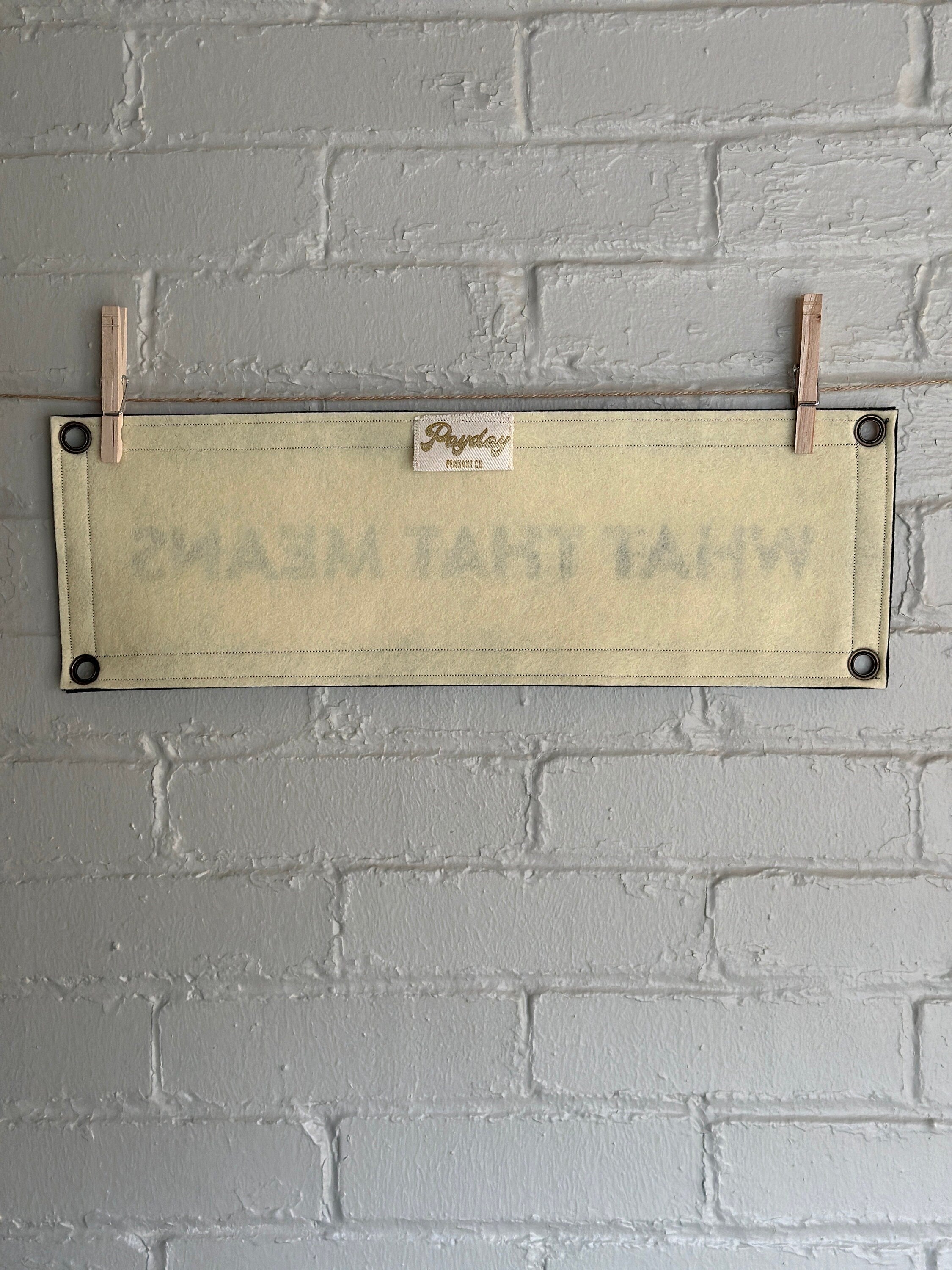 Back of a cream banner with black trim and text that reads "WHAT THAT MEANS"