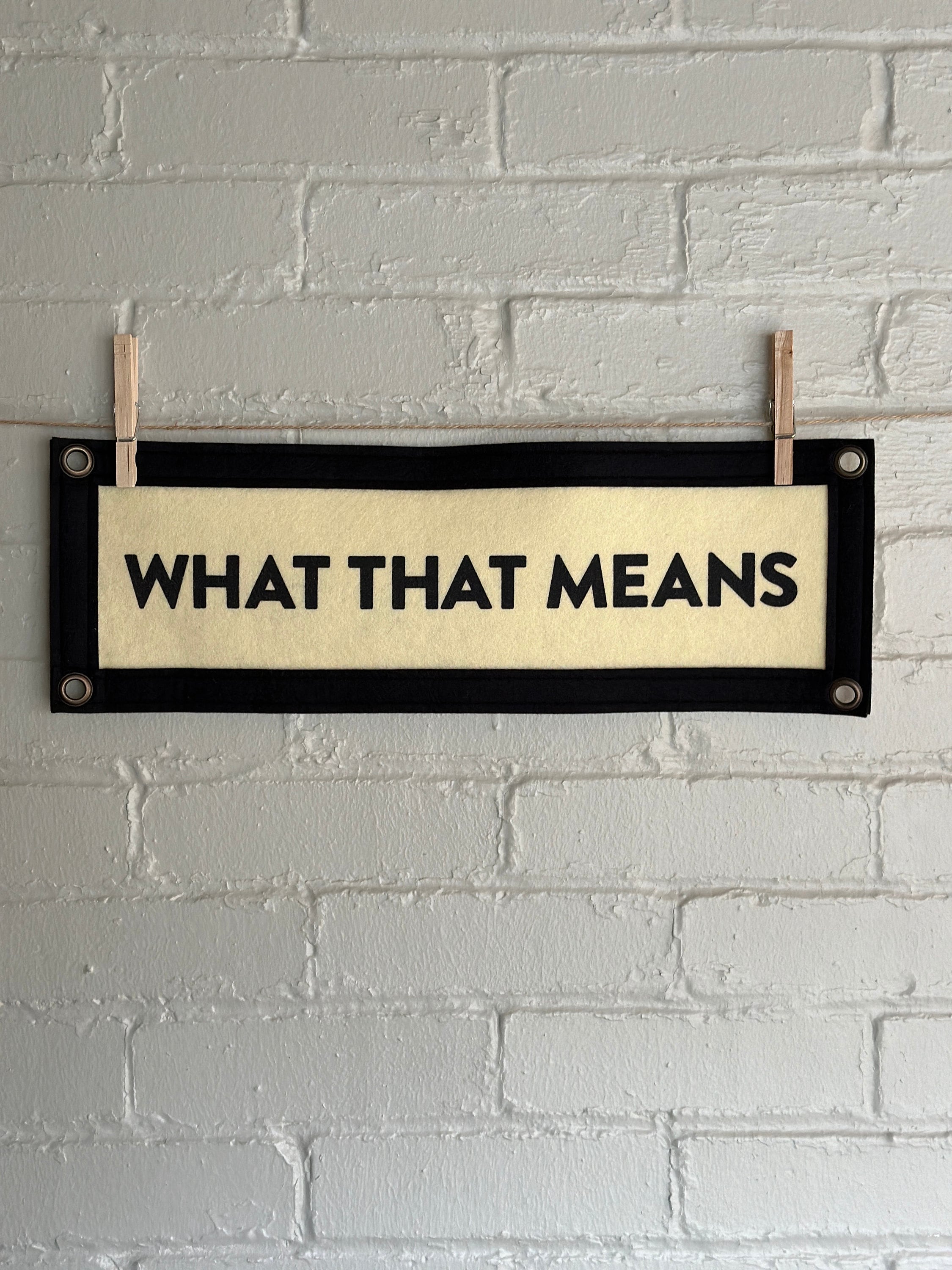 A cream banner with black trim and text that reads "WHAT THAT MEANS"
