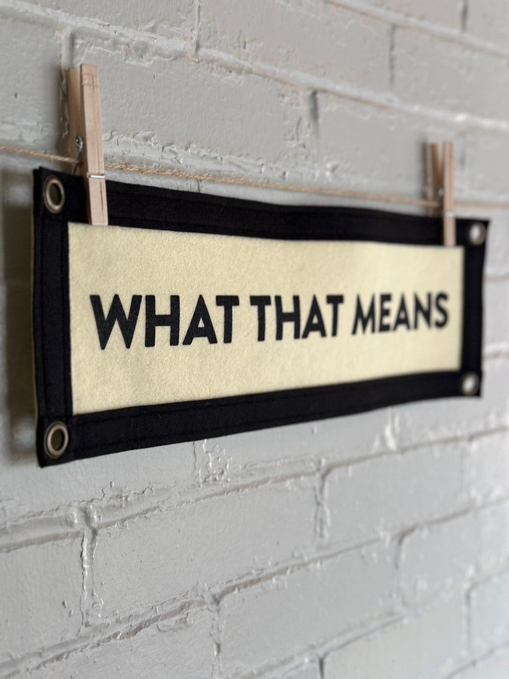 Side of a cream banner with black trim and text that reads "WHAT THAT MEANS"