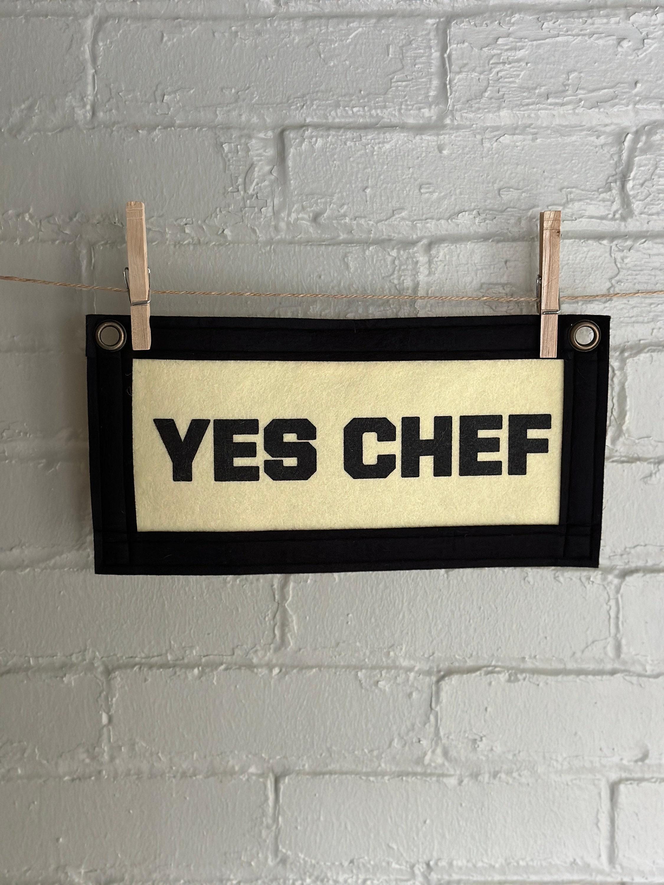 A cream felt banner with black trim and black print reading "YES CHEF"