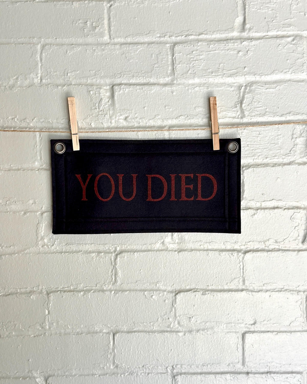 A black felt banner with black trim and red lettering that reads 'YOU DIED'