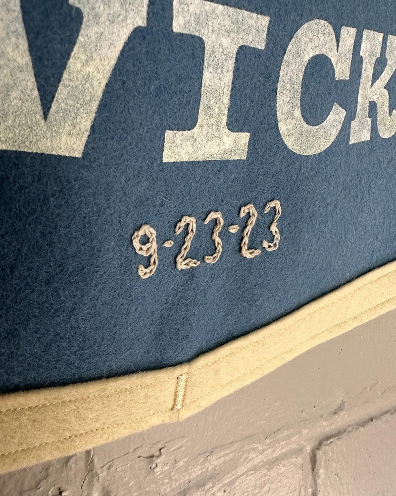 A close up of a wedding date stitched into a blue felt banner.