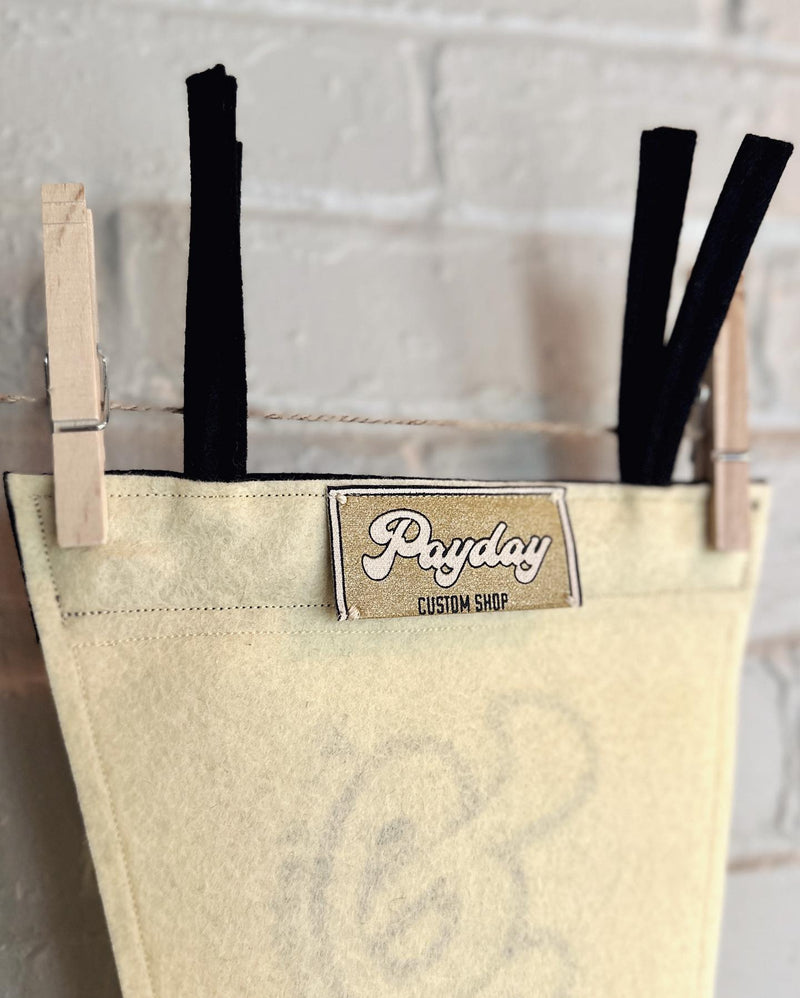The back of a cream pennant with a golden Payday Custom Shop tag.