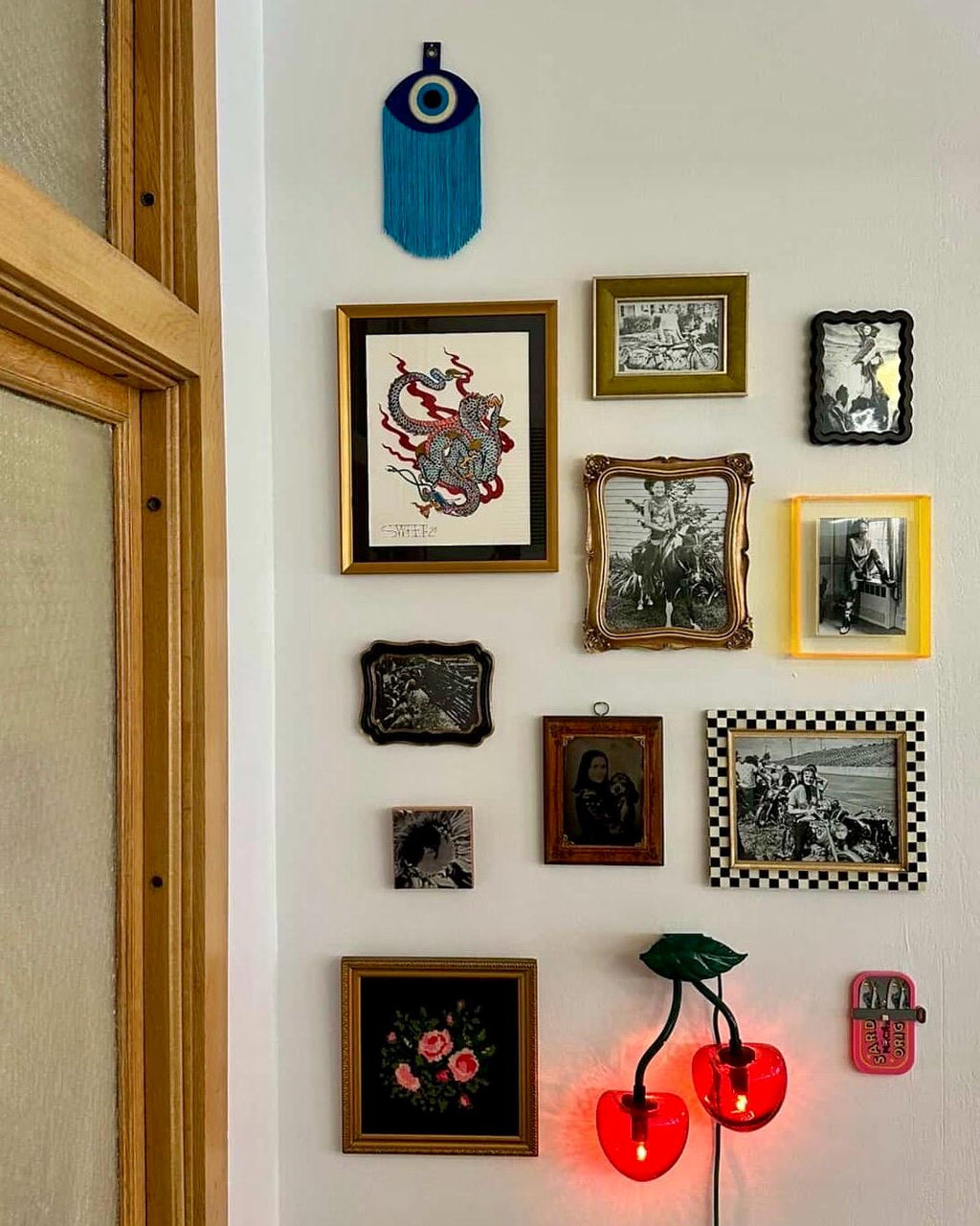 A felt "evil eye" displayed on a gallery wall alongside other framed artwork