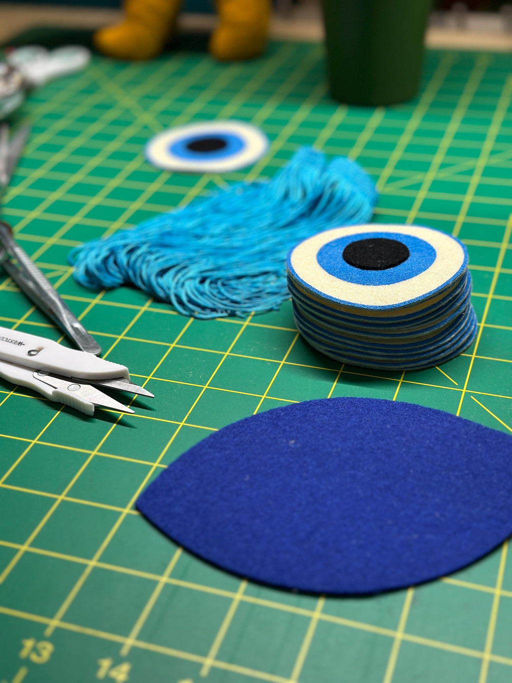 Various components of a felt "evil eye" on a cutting table