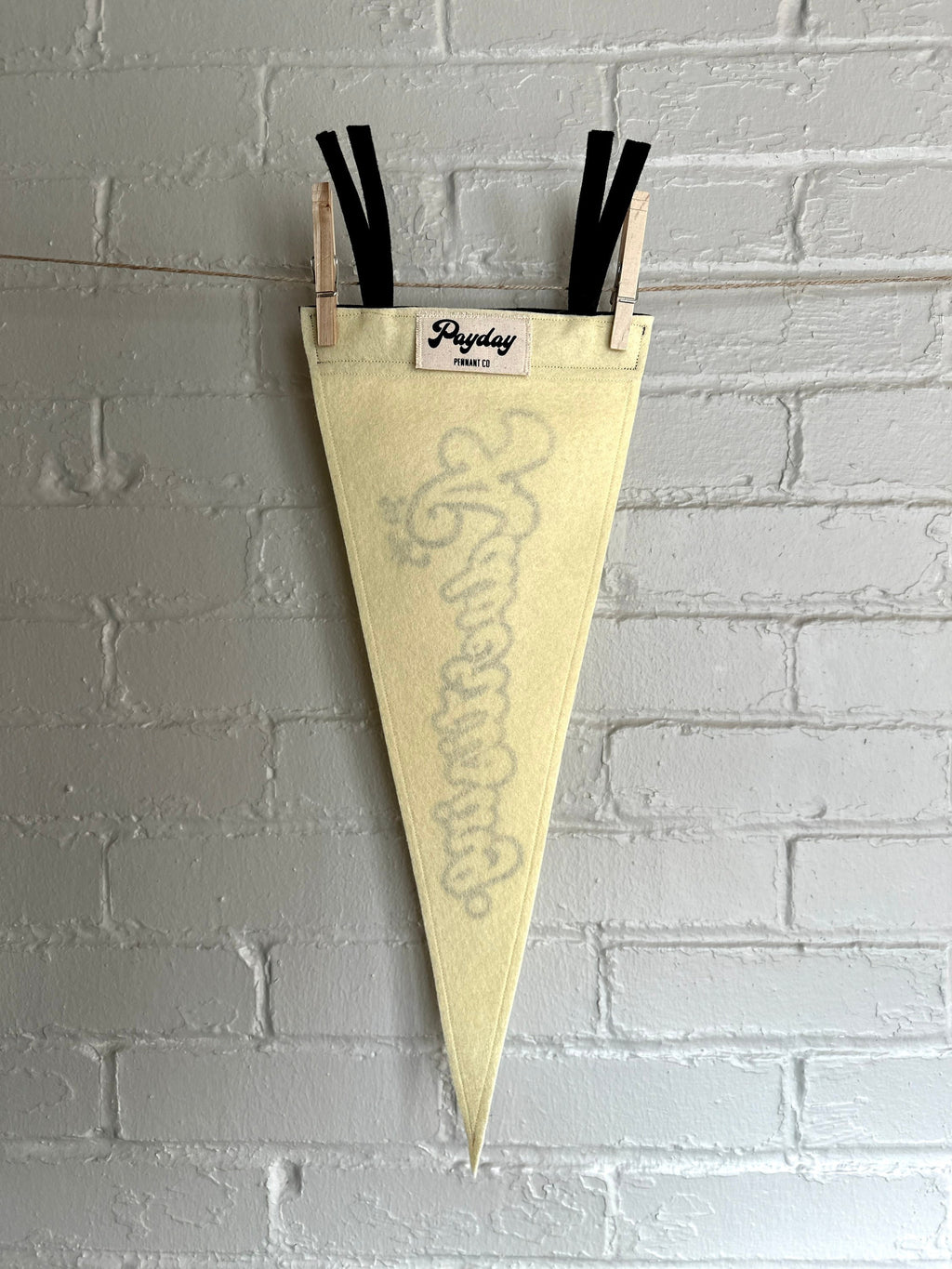The back of a cream felt pennant with black trim and print that reads "It's just advertising"