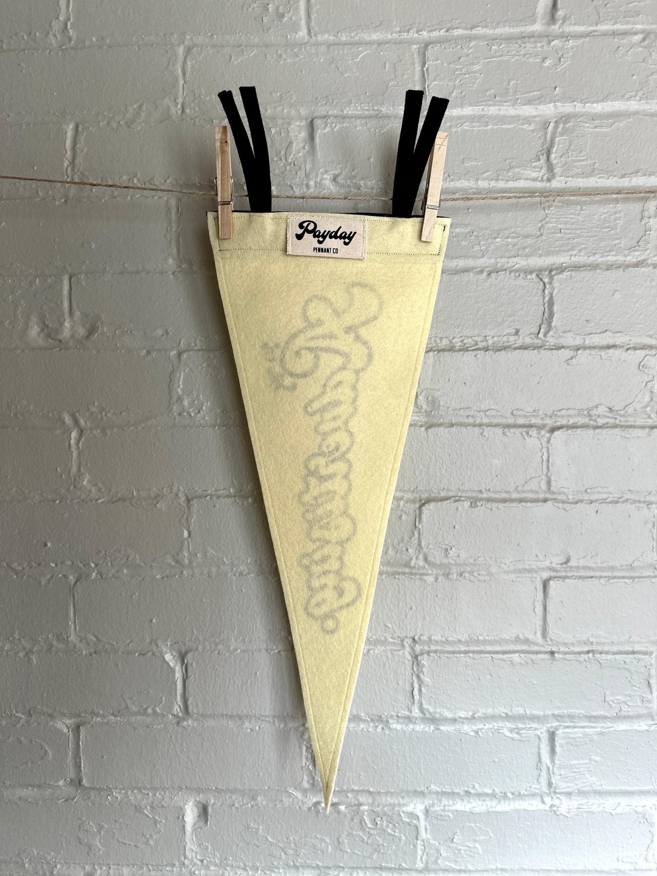 The back of a cream felt pennant with black trim and print that reads "It's just advertising"