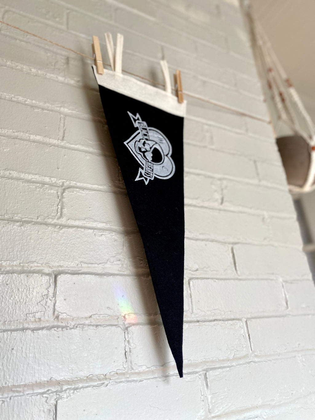 A side view of a black pennant with white trim and the Venture Bros "Black Hearts" logo printed on
