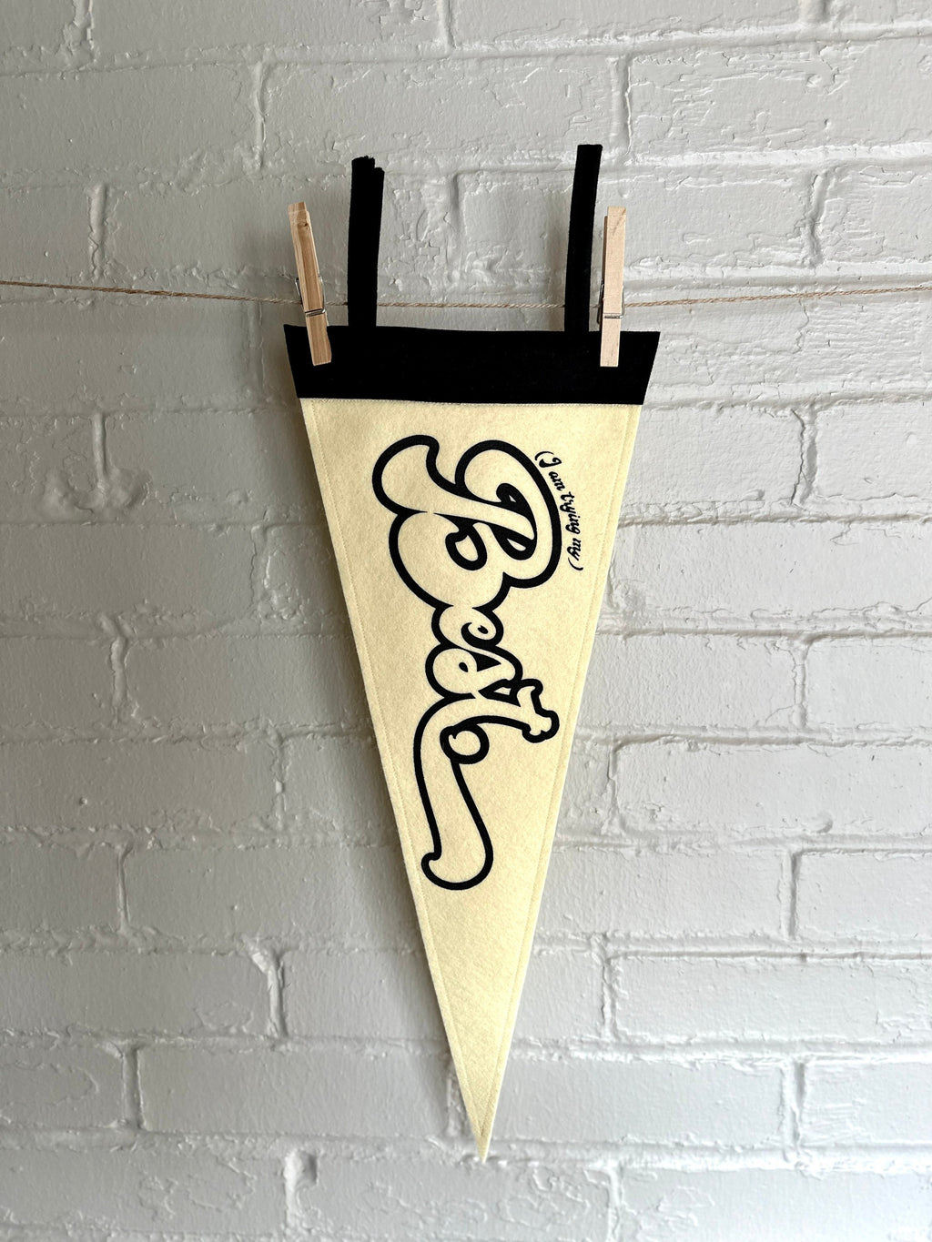 A cream felt pennant with black trim and black lettering that reads "I'm trying my best"